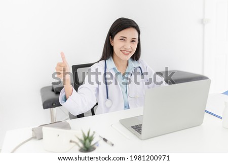 asian female doctor search information and typing report with laptop, she show thumbs up sign with hand, medical knowledge technology, happiness hospital