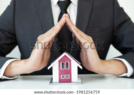 The house is covered by the hands of a real estate agent to protect the house for customers, homebuyers, insurance, ready give to with new owner. Real estate Home insurance concept.