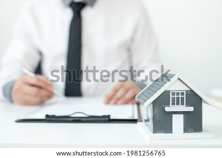 Agents working in real estate investment and home insurance signing contracts in accordance with the home buying insurance agreements approving purchases for clients.