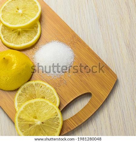 Lemon slices and white granulated sugar on a wooden kitchen board. Lemon is a cure for colds. Side and top view, copy space.