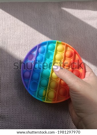 anti-stress colorful toy comes out of the shadows. Close-up with colorful pop It fidget toy, sun rays and shadows on anti-stress toys. High quality photo