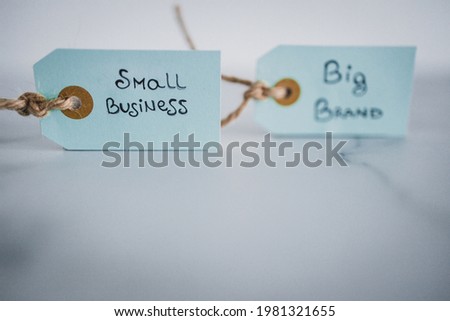 product tags with small business vs big brand texts side by side sho at shallow depth of field, concept of customer behaviour and supporting small businesses