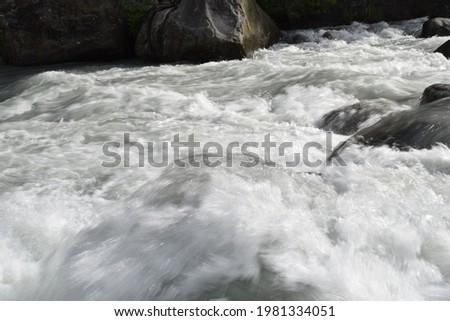 A picture of beautiful Beas river flowing through the Himalayan mountains in Manali, cutting through forests and rocks.