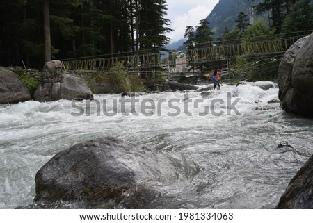 A picture of beautiful Beas river flowing through the Himalayan mountains in Manali, cutting through forests and rocks.