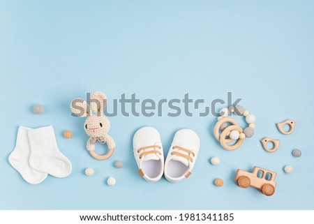 Baby shoes, bib and teether on pastel background. Organic newborn accessories Royalty-Free Stock Photo #1981341185