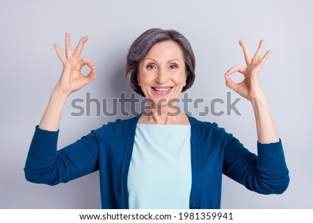 Photo portrait of smiling happy senior woman showing okay gesture both hands isolated on grey color background