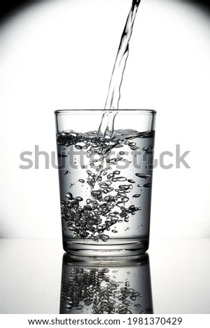 Pouring natural mineral water from bottle into glass. Isolated and white background. In summer 