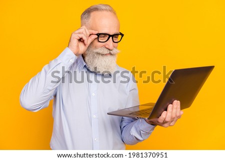 Photo of concentrated old charming man look laptop smile wear glasses isolated on yellow color background