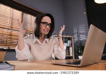 Emotional businesswoman working on laptop in office. Online hate concept