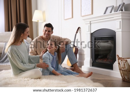 Happy family resting near fireplace at home