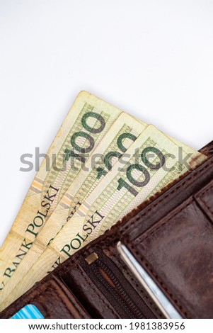 Lots of Polish banknotes sticking out of a brown leather wallet. Photo taken under artificial, soft light, objec isolated on white background