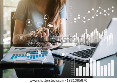 Businesswomen or Designer using tablet with laptop and document on desk in modern office with virtual interface graphic icons network diagram.