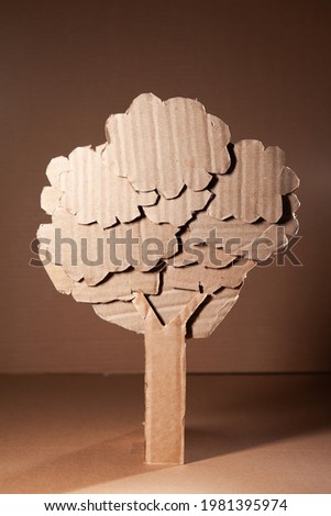 Beautiful light on a tree made of cardboard on a degrade background. Children art project. DIY concept. Cardboard craft.