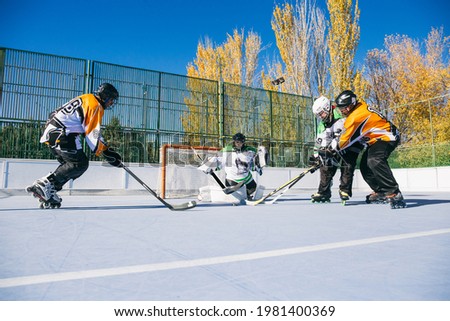 In-line hockey players attacking the gates of opposite team in sunny day. 