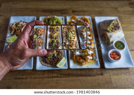 Man takes a photo of Mexican food dishes on the restaurant table