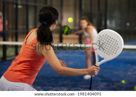 Rear view of brunette girl with white racket playing padel tennis at court Royalty-Free Stock Photo #1981404095