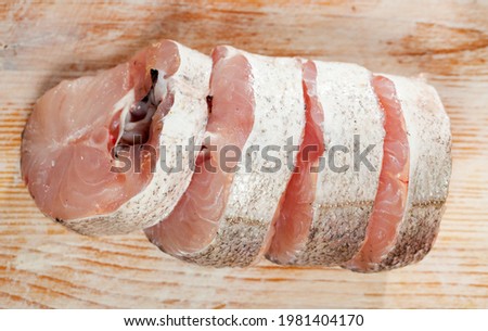 Fresh raw sliced whiting fish ready for cooking on wooden background..