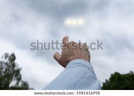 Man pointing finger at the strange lights in the sky, three light orbs among the clouds, UFO concept Royalty-Free Stock Photo #1981416998