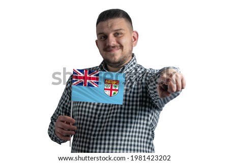 White guy holding a flag of Fiji and points forward in front of him isolated on a white background.