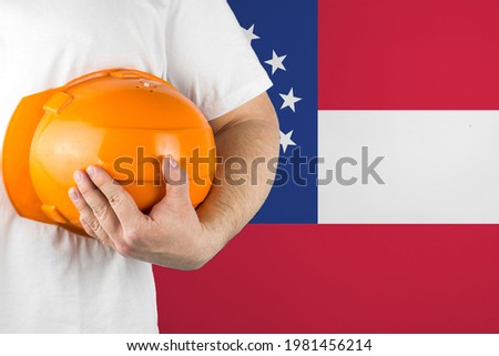 Worker with Georgia flag on background for working on labor day. Construction concept.