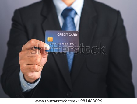 Businessman holding a mockup blue credit card while standing in a studio with copy space for text. Close-up photo. Money and business concept.