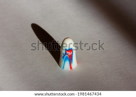 multi-colored foam earplug on a white background with shadows