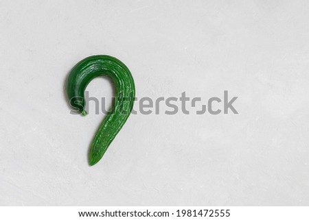 Funny ugly cucumber shapes as question mark on neutral background. Image with copy space, top view Royalty-Free Stock Photo #1981472555
