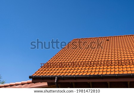 Red corrugated metal profile roof installed on a modern house. The roof of corrugated sheet. Roofing of metal profile wavy shape. Modern roof made of metal. Metal roofing.