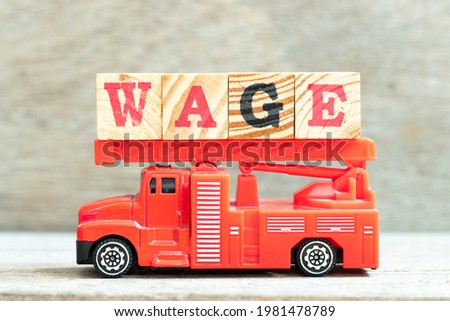 Fire ladder truck hold letter block in word wage on wood background