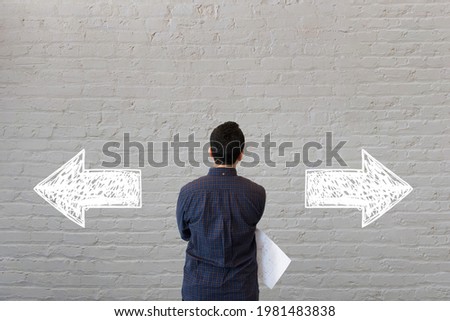 Young Entrepreneur. Man staring at wall with arrows pointing directions.