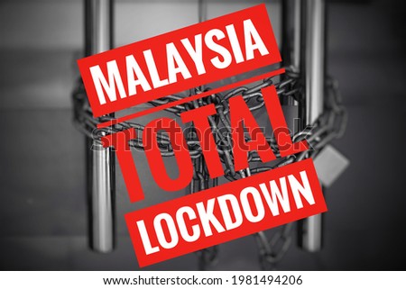 Text spelling 'Malaysia Total Lockdown' on blurred chain locked background. Lock down and covid19 prevention concept.