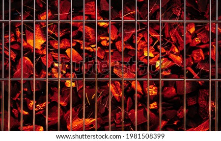Red and hot pieces of coals or smolders under grill grate. Top view.