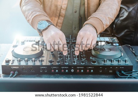 Disc jockey hands playing music for tourist people at beach party outdoor - Live event, music and fun concept - Entertainment and party concept Royalty-Free Stock Photo #1981522844