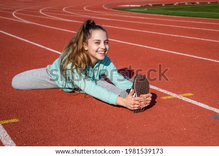 Sporty beauty. confident flexible athlete. teen girl warming up on stadium. kid in sportswear stretching. child do split exercise on racing track. healthy childhood. workout on fresh air outdoor