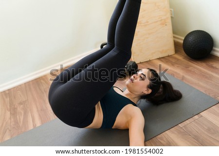 Power training at home. Fit woman doing reverse crunches exercises to strengthen her abdomen and core body during a cardio workout Royalty-Free Stock Photo #1981554002
