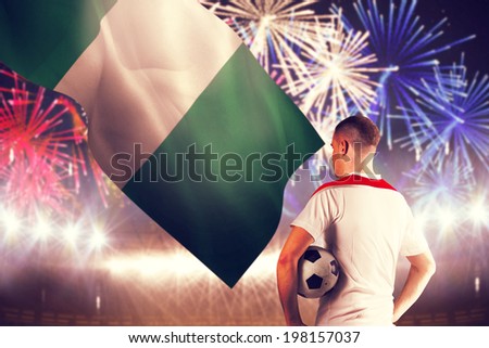 Football player holding the ball against fireworks exploding over football stadium