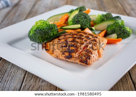 A view of a plate of grilled salmon and steamed vegetables.