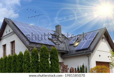Solar panels on a gable roof. Beautiful, large modern house and solar energy. Rays of the sun. Royalty-Free Stock Photo #1981585070
