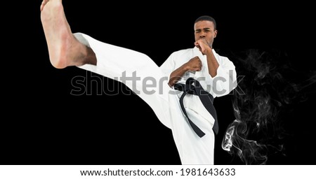 Composition of male martial karate artist with black belt kicking over smoke and copy space. sport and competition concept digitally generated image.