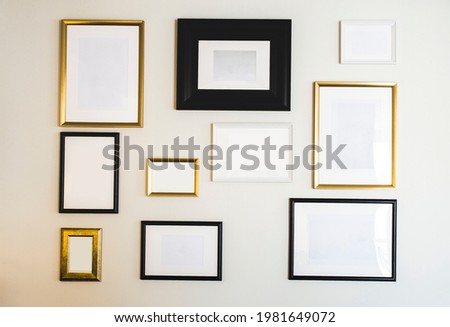 Empty gold and black photo and picture frames on white wall, mock up for your photos or text, copy space modern design luxury decoration closeup