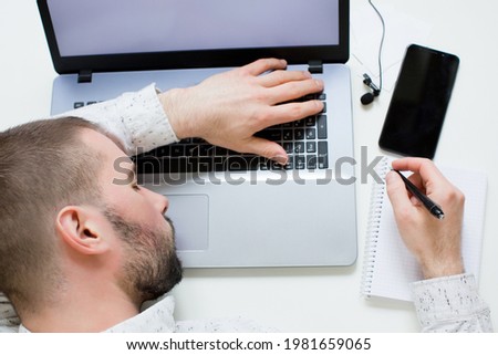 Tired man sleeping on laptop. Work concept. Laptop, smartphone and lapel microphone on a white background