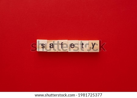 word SAFETY made of wooden letters on red background with copy space.