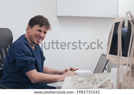 Orthopedist doctor examining X-ray picture at desk in clinic on laptop computer