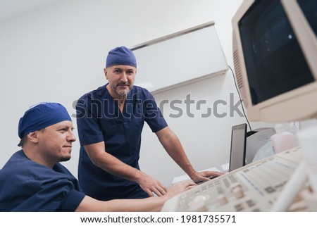 Orthopedist doctor team examining digital X-ray picture in clinic on a laptop computer