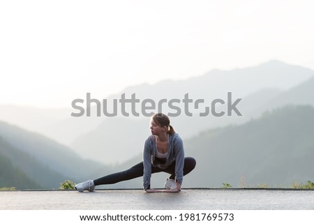 Adult Female workout before fitness training session at the top of the mountain. Woman warming up outdoors. 
