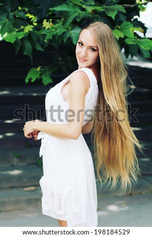 Portrait of charming young girl with long hair. Attractive young woman walking in a park on a sunny day