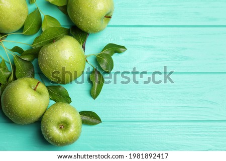 Fresh ripe green apples with water drops on turquoise wooden table, flat lay. Space for text