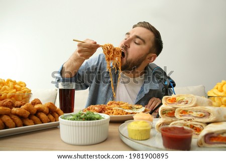 Food blogger eating in front of microphone at table against light background. Mukbang vlog Royalty-Free Stock Photo #1981900895