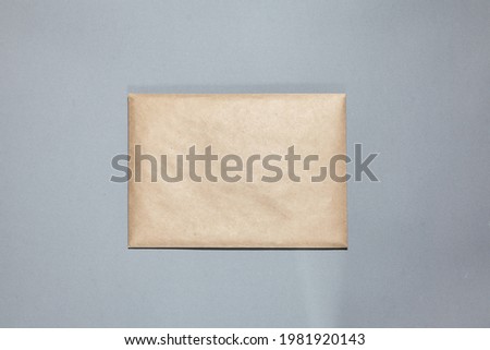 A brown craft envelope on gray background. Closed craft envelope, branch on gray table. Invitation card mockup. Flat lay, top view, copy space, mockup
