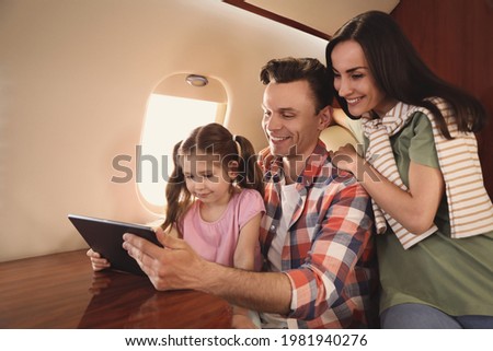 Happy family using tablet in airplane during flight